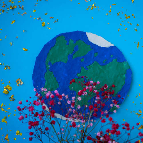 Painting of the world on a blue background with gold glitter and pink and red flowers on top.