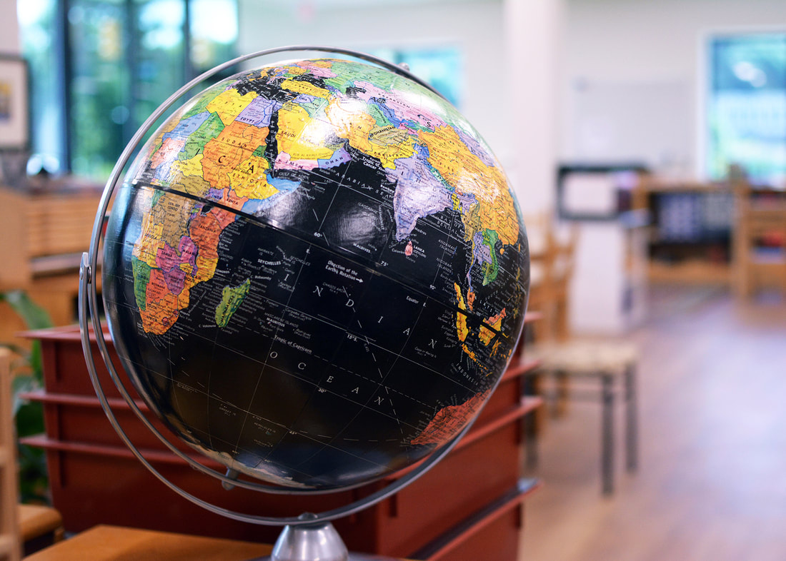 A globe with a brightly lit classroom in the background