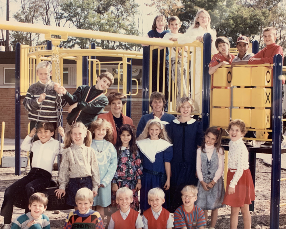 An original photo from the first years of TMS opening. Pictured are 23 students and staff in front of and on playground equipment.