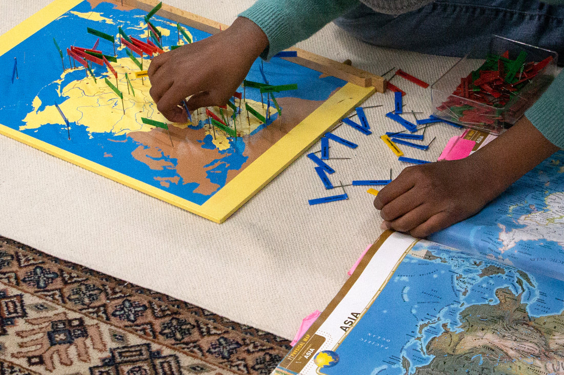 Older student's hands are shown adding flags to the correct location on a map to practice the geography of Asia.