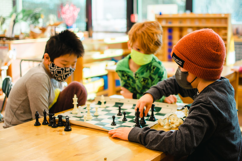 Three children engaged in a game of chess